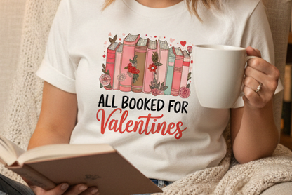 White t-shirt with Valentine's Day design featuring books and flowers, next to denim jeans and a watch.